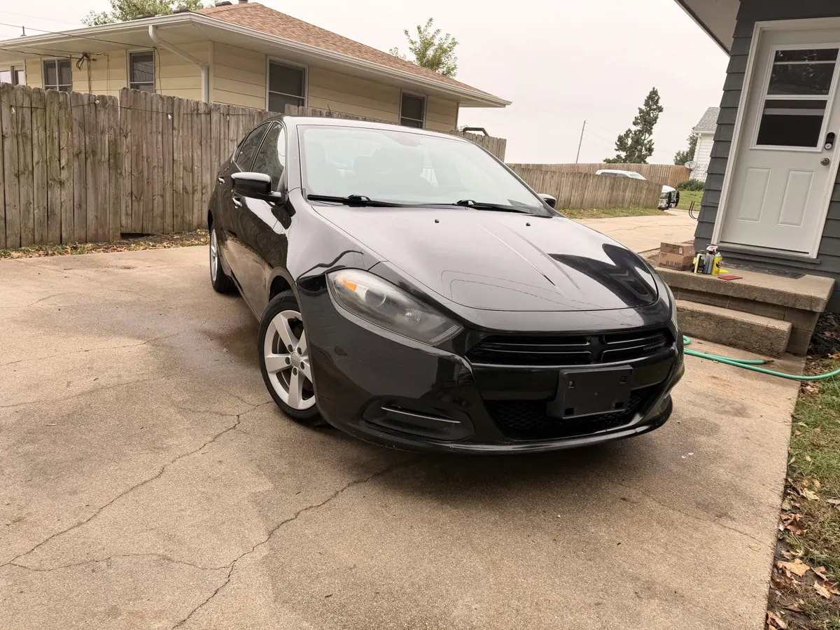 Black Dodge Dart sedan in a driveway after service