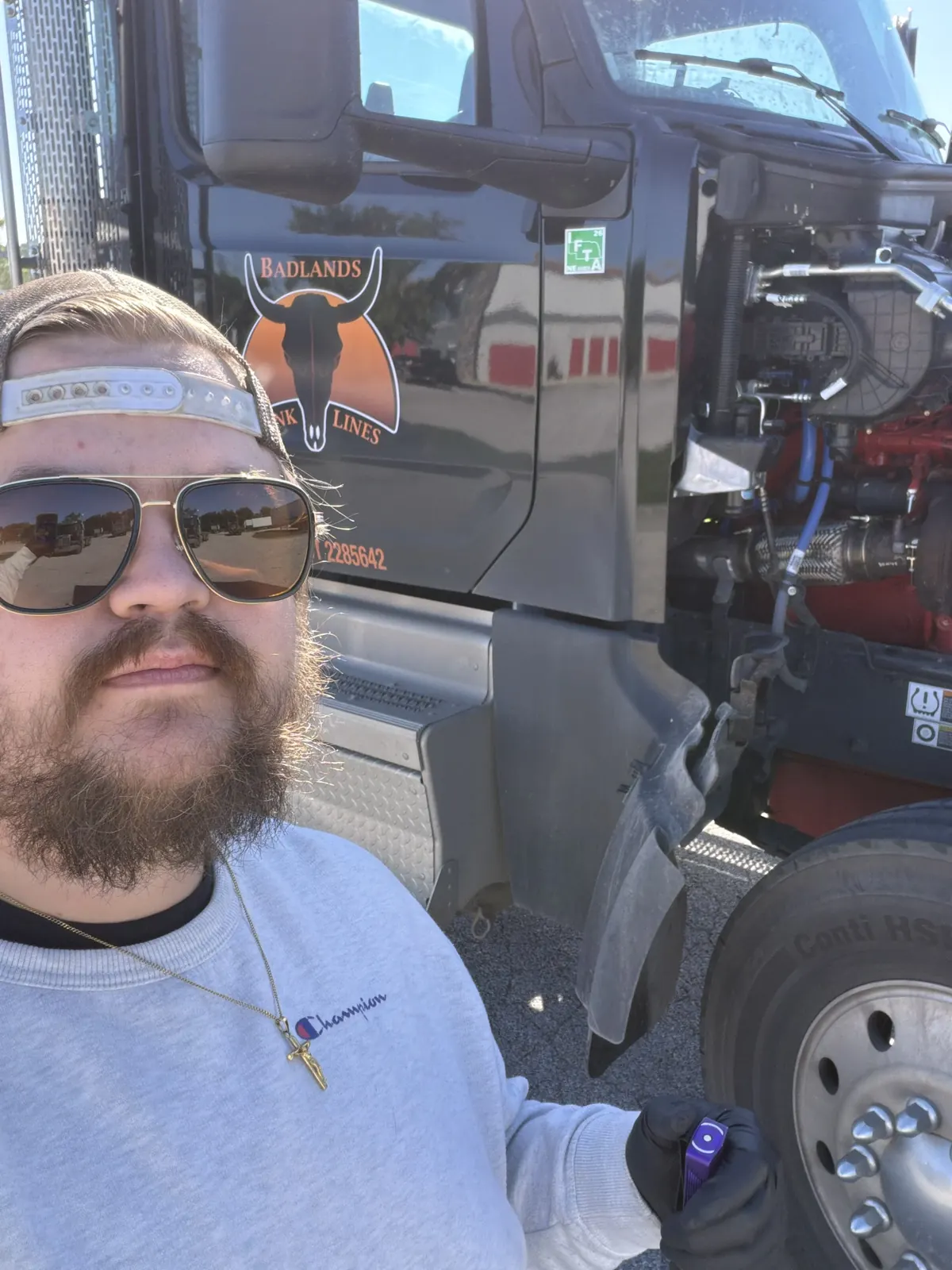 CNL Auto Works mechanic beside a semi truck with the hood open during on-site service